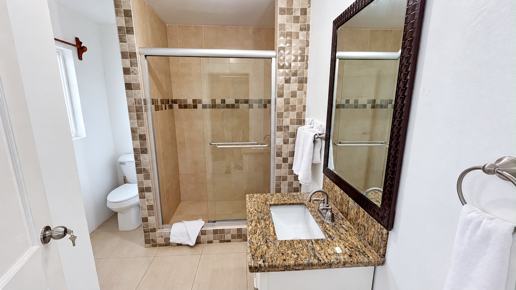 Grand Pavilion ensuite bathroom with a glass shower, granite vanity, mirror and natural window light.