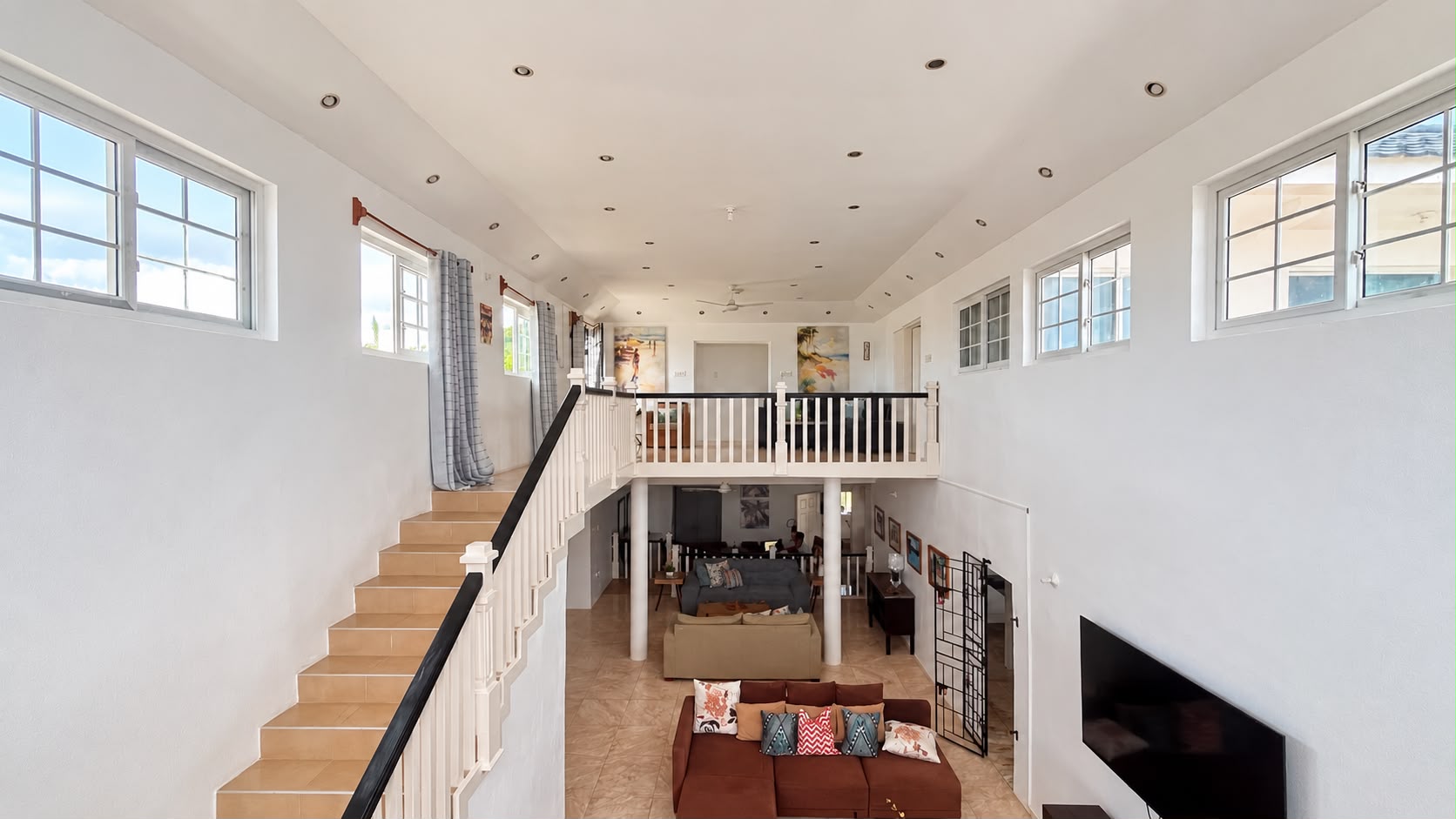 Bright upper landing at Da Villa Juanita’s Grand Pavilion, overlooking the open living area and ocean-facing windows.